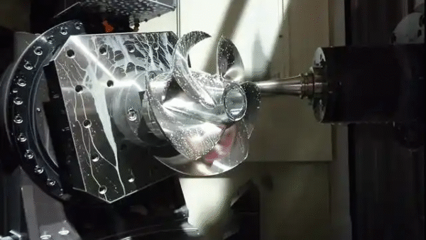 CNC 5-axis machined metal part in process, showing multi-axis precision cutting, complex geometry, and advanced manufacturing technology.